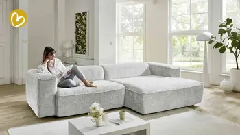 Frau sitzt entspannt auf einem Sofa und ließt ein Möbelmagazin